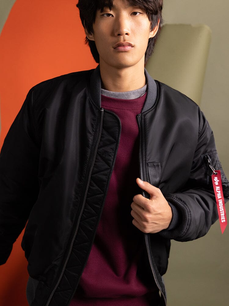 Person wearing the 1960s MA-1 Bomber Jacket in black by Alpha Industries.