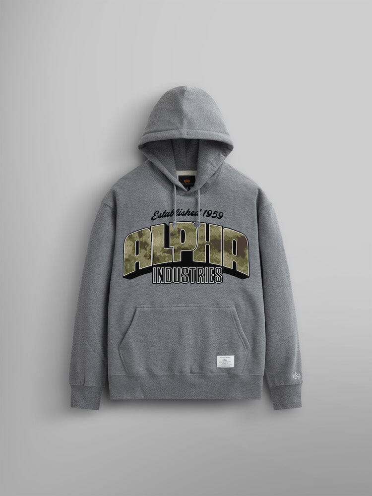 The Alpha Camo Logo Hoodie by Alpha Industries in charcoal heather. This unisex hoodie features the Alpha Industries camo logo prominently on the front with "Estab. Since 1959" above it. Crafted from heavy cotton, it includes a front pocket and a small label at the hem.