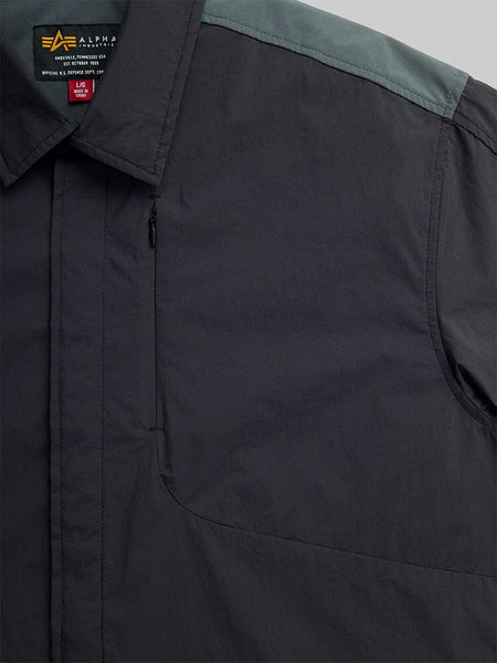 Close-up of the Astral Shirt Jacket by Alpha Industries. The shirt jacket is black featuring a concealed zipper pocket on the chest.