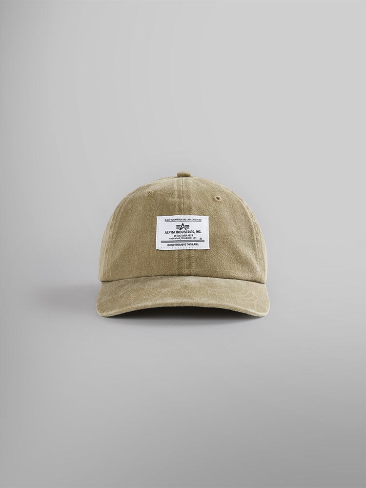 The Battlewash Cap by Alpha Industries in olive, featuring a vintage-inspired design with a white rectangular patch on the front, embellished with text and a small Alpha logo.