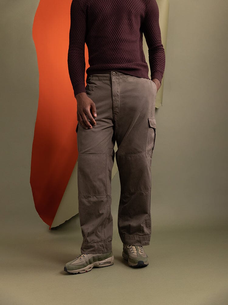 A person wearing a maroon sweater and the Belgian M-64 Pant in brown by Alpha Industries.