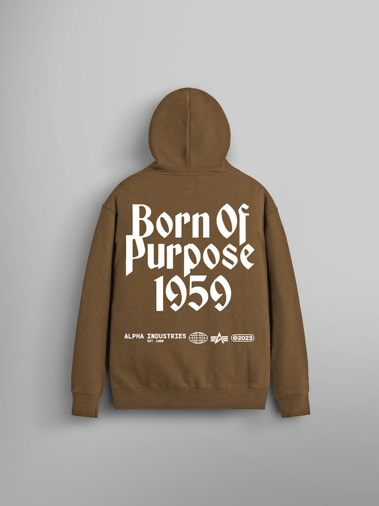 The Born Of Purpose Hoodie by Alpha Industries is made from heavy cotton and boasts a coyote brown color. It showcases "Born Of Purpose 1959" along Alpha Industries logos on the back.