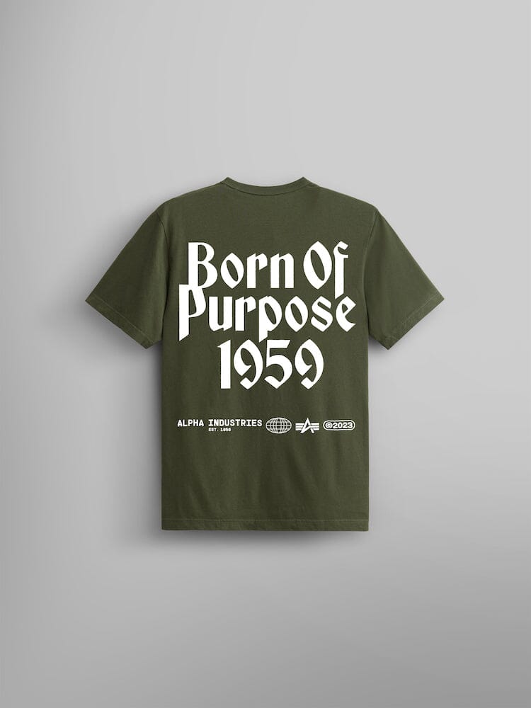 The Born Of Purpose Tee by Alpha Industries in olive green with "Born Of Purpose 1959" prominently displayed in large white screen print on the back. The Flying A logo and additional logos are featured below the text.