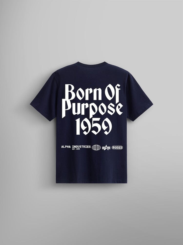 The Born Of Purpose Tee by Alpha Industries in replica blue, showcasing a bold screen print of "Born Of Purpose 1959" in prominent white letters on the back. Iit also features additional logos and text below, accented by the iconic Flying A logo.