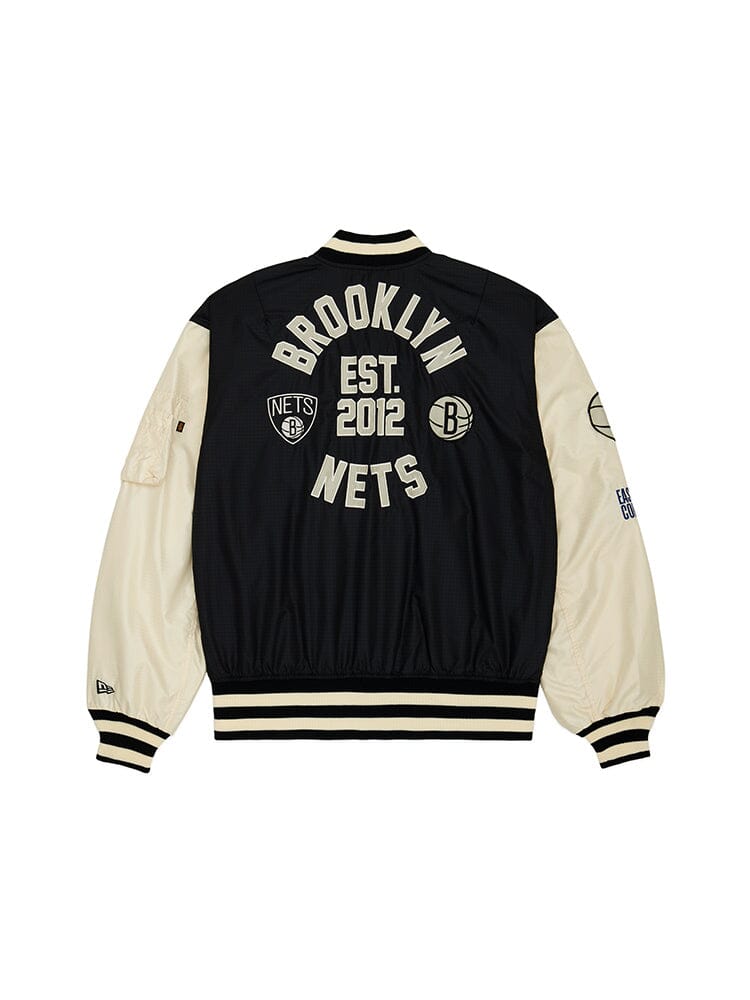 The back of the Brooklyn Nets x Alpha X New Era L-2B Bomber Jacket showcases a black and white design with team patches, Brooklyn Nets text, Est. 2012 details, and logos. This NBA Bomber Jacket from Alpha Industries is further elevated by its pinstripe interior for extra style.