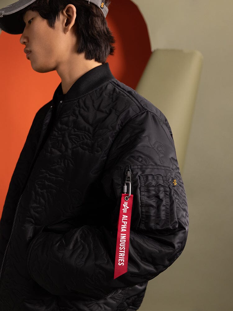 Side view of a person wearing a Camo Quilted MA-1 Bomber Jacket in black by Alpha Industries.