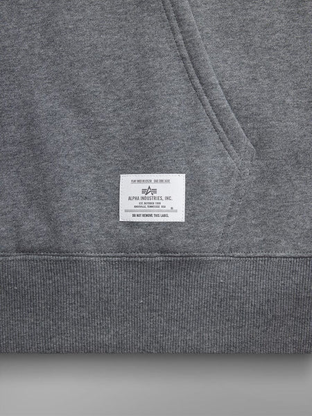 Close-up of a medium charcoal heather grey unisex Essential Hoodie, featuring a white label with the Alpha Industries logo.