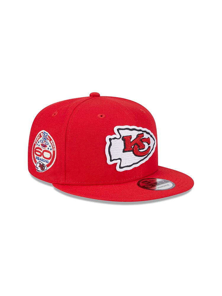 The Kansas City Chiefs x Alpha x New Era 950 Cap by Alpha Industries showcases a striking red design featuring the iconic KC team logo on the front and a unique 60th anniversary patch on the side.