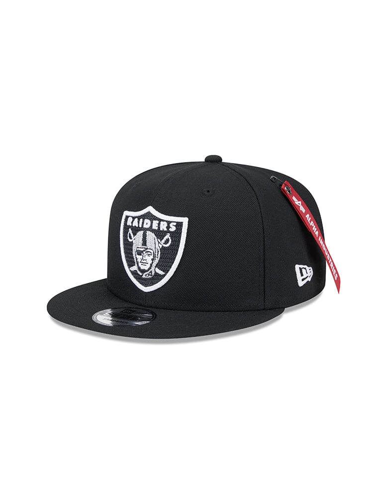 The Las Vegas Raiders x Alpha x New Era 950 Cap, designed in collaboration with Alpha Industries, boasts a bold team logo on the front and includes a distinctive red tag on the visor. This black New Era snapback is an essential accessory for both fans and fashion enthusiasts.