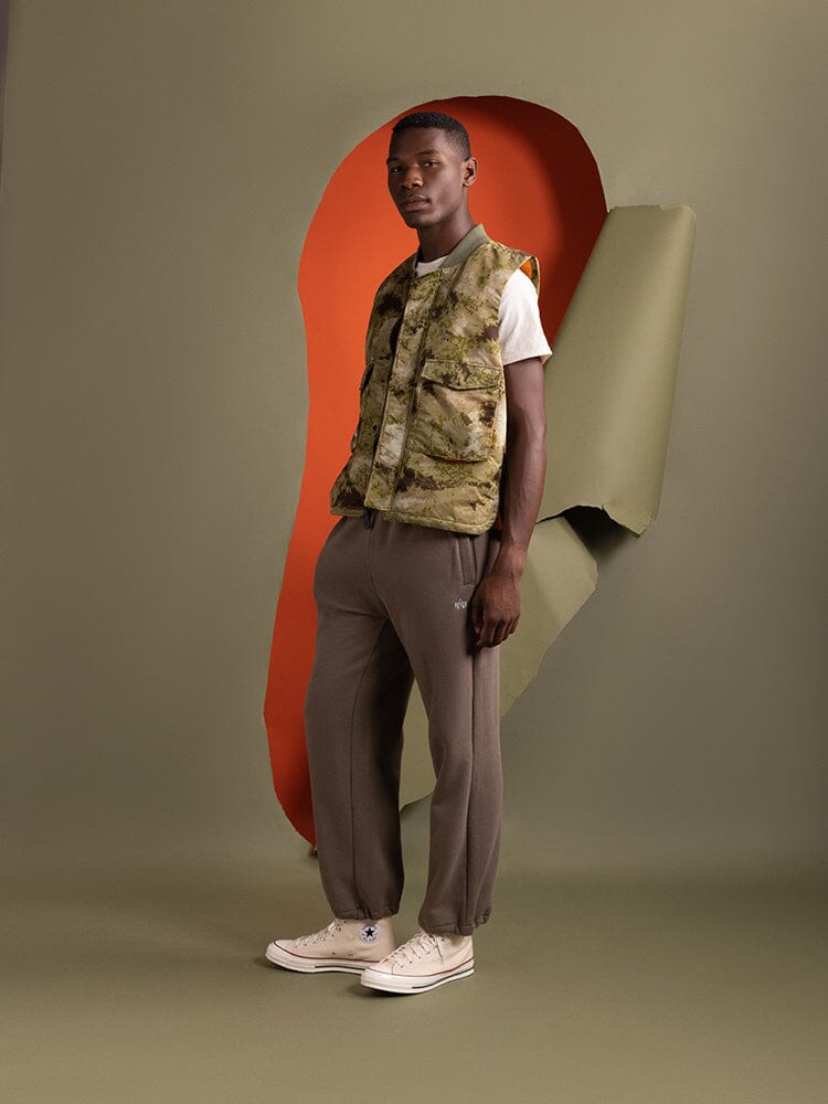 Side view of a person wearing an Alpha Industries MA-1 Mod Vest in green blur camo, which features quilted lining and a flight nylon exterior.