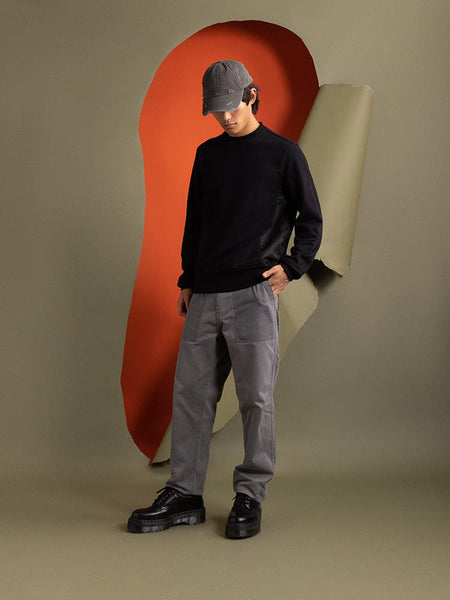 An person dressed in a Mixed Media Crewneck Sweatshirt in black by Alpha Industries, featuring nylon patches.