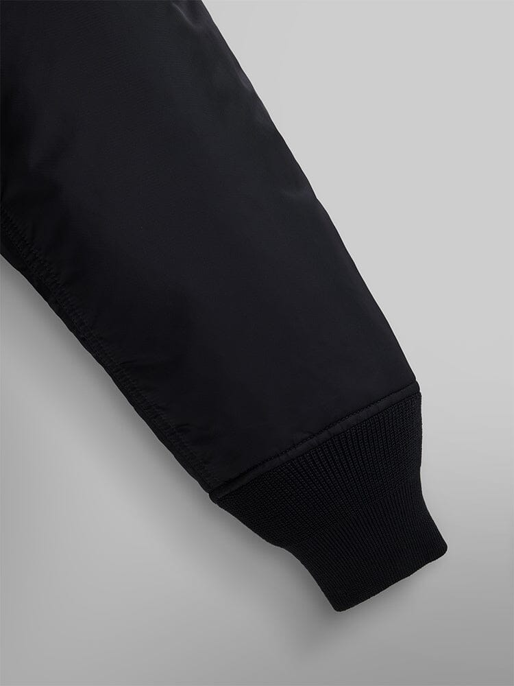 Close-up of a sleeve from the Alpha Industries Mixed Media Quilted Utility Jacket in black, featuring a ribbed cuff.