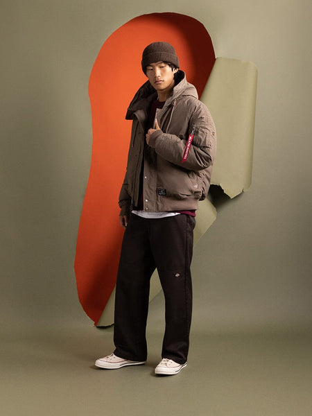 A person standing to the side wearing the N-2B Altitude Parka in brown by Alpha Industries.