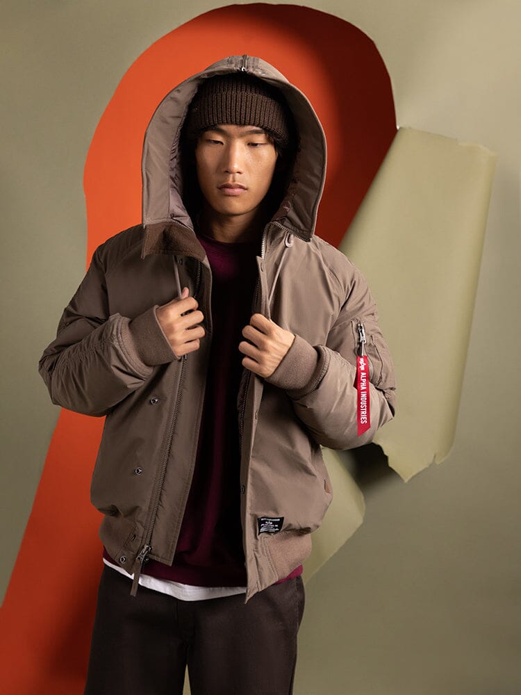 A person wearing the N-2B Altitude Parka in brown, by Alpha Industries, with a focus on the hood and draw strings.