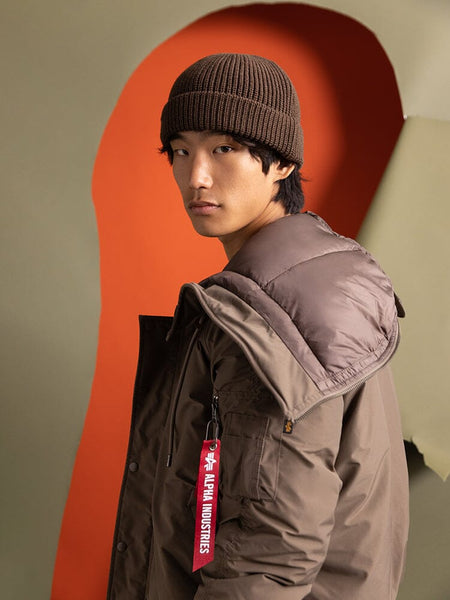 A person standing to the side wearing the N-2B Altitude Parka by Alpha Industries.