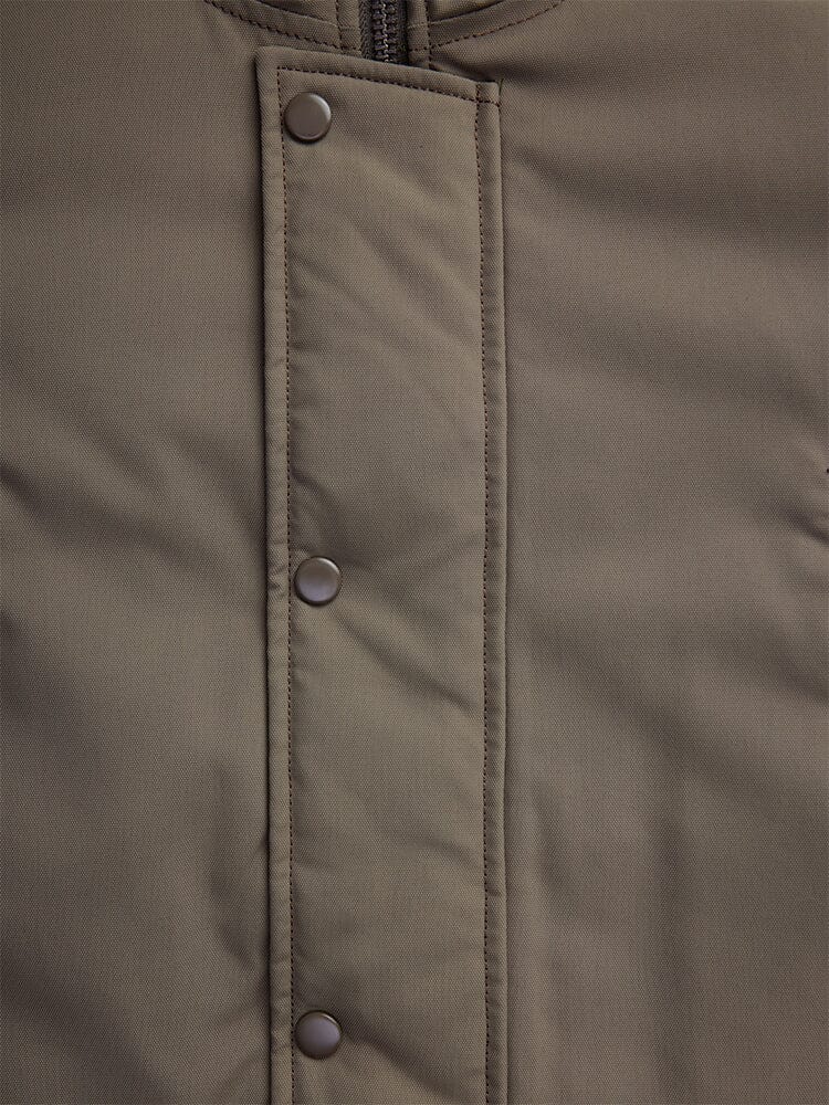 Close-up of the N-3B Altitude Mod Parka in brown by Alpha Industries, featuring a water-resistant fabric for added durability, with a zipper and metal snap buttons along the front flap.