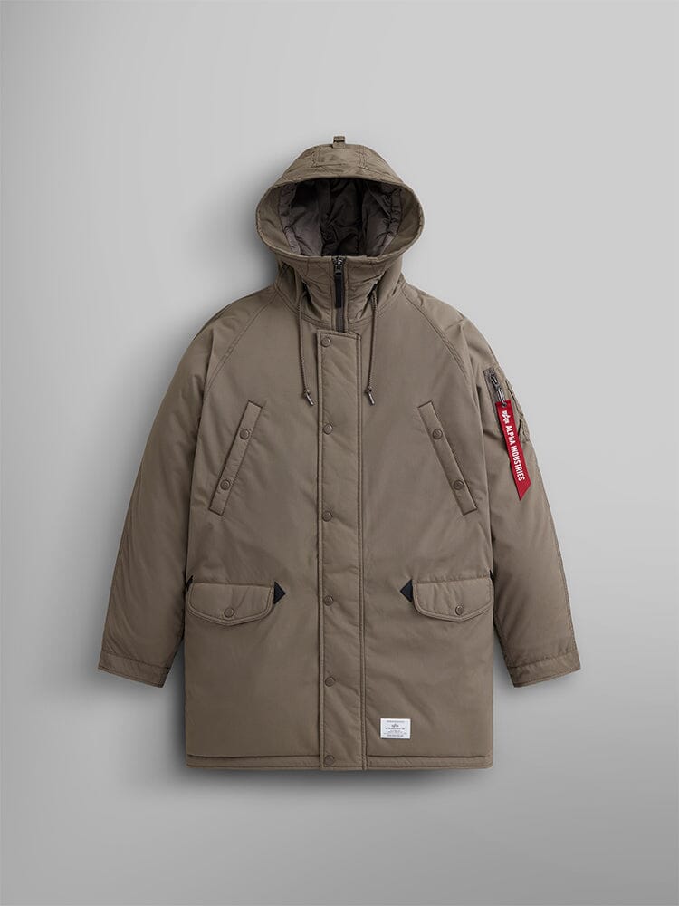 The N-3B Altitude Mod Parka by Alpha Industries, in a coyote brown color, showcases a buttoned front, two large pockets, and a striking red zipper tag on the left sleeve.