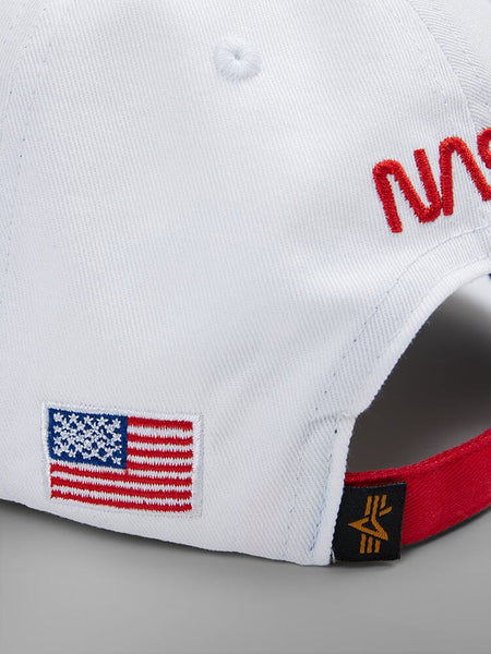 Back side view of The NASA Worm Logo Cap by Alpha Industries. This white cap is adorned with a striking red NASA worm logo, an American flag patch, and a subtle star on the brim.