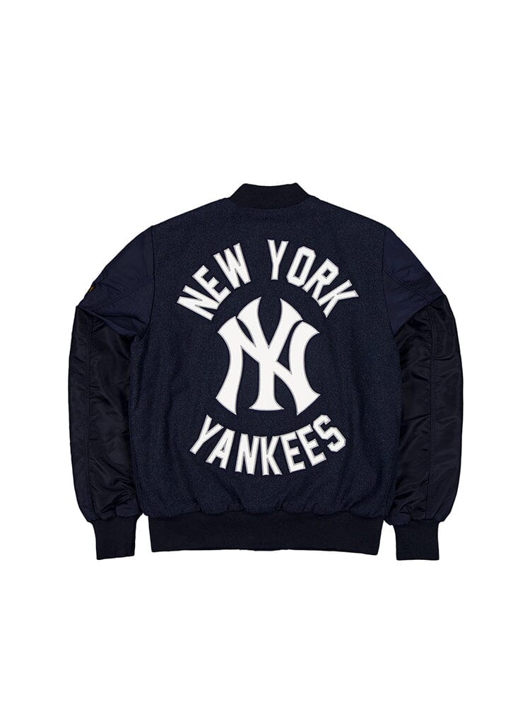 The New York Yankees x Alpha x New Era MA-1 Bomber Jacket by Alpha Industries features quilted lining for added warmth and showcases a large white logo and text on the back, all in a sleek navy blue design.