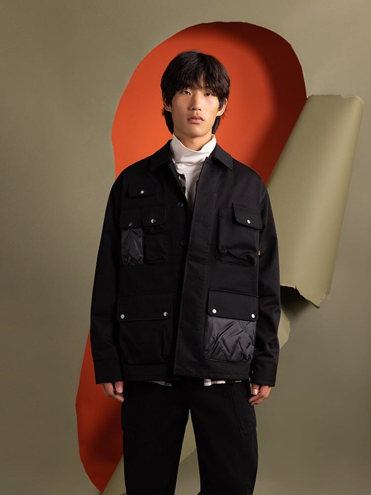 A person wearing the Onion Quilted Mixed Media Shirt Jacket in black from Alpha Industries.