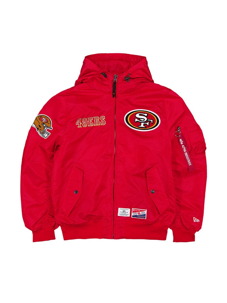 The San Francisco 49ers x Alpha x New Era L-2B Bomber Jacket, in a striking red color, prominently features the team's logo along with embroidered text and intricate NFL team patches on the sleeve, brought to you by Alpha Industries.