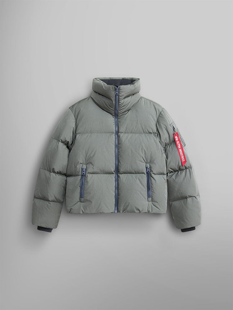 The Sierra Short Puffer W by Alpha Industries in Field Gray is a water-resistant puffer jacket with a high collar and front zipper, featuring side pockets and a distinctive red tag on the left sleeve.