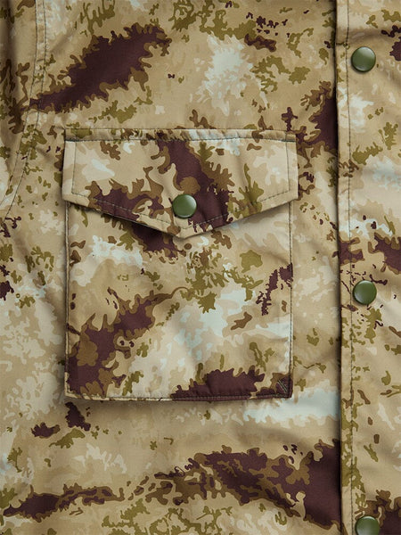 Close-up of the Tactical M-65 Field Jacket, a camouflage-patterned fabric field coat from Alpha Industries, showcasing a front pocket and green buttons.