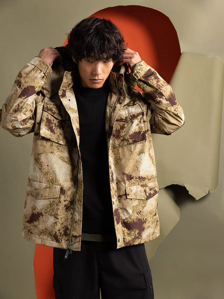 A person wears an Alpha Industries Tactical M-65 Field Jacket in green camo with a hood.