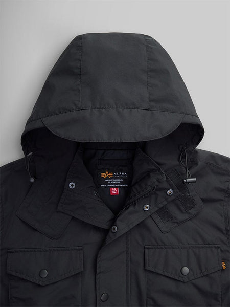 Close-up view of the Tactical M-65 Field Jacket in black by Alpha Industries, designed with multiple pockets and a partially visible front zipper, offering water resistance and a hooded feature.