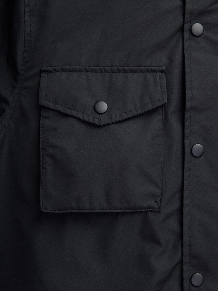 Close-up of the Tactical M-65 Field Jacket in black by Alpha Industries, showcasing a front buttoned pocket and additional buttons along the seam.