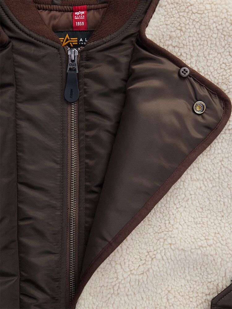 Close-up of the Women's B-15 Sherpa Hybrid Bomber Jacket in brown by Alpha Industries. Featuring a classic button closure and striking asymmetrical zipper details.