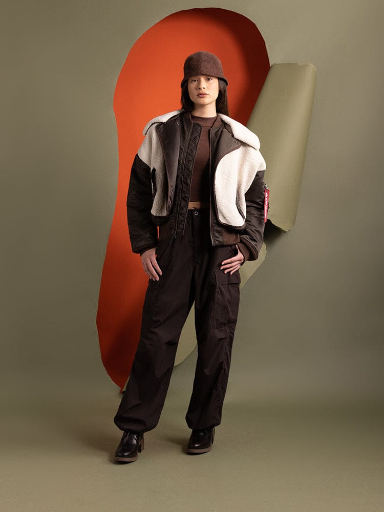 A person wearing the Women's B-15 Sherpa Hybrid Bomber Jacket in brown by Alpha Industries.