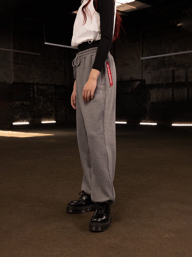 Side view of a person wearing Women's Essential Sweatpants in medium charcoal heather (gray) by Alpha Industries.