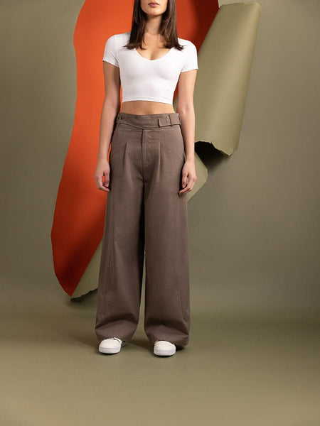 A woman stands wearing the Women's Gurkha Wide Leg Trouser in brown by Alpha Industries.