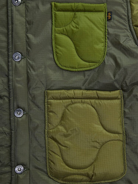 Close-up of the Women's Insulated Chore Coat by Alpha Industries, showcasing green onion quilting fabric with intricate stitching details, highlighted by buttons and two patch pockets in varying shades of green.