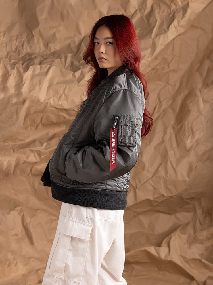 Side-view of a person wearing the Women's MA-1 Shirring Bomber Jacket by Alpha Industries, showcasing a utility pocket.