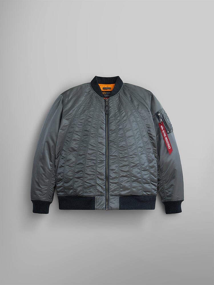 The Women's MA-1 Shirring Bomber Jacket by Alpha Industries showcases a vintage-inspired design in field gray. Crafted from durable nylon, it features black cuffs and collar. The jacket includes a utility pocket on the left sleeve, highlighted with a bold red tag.