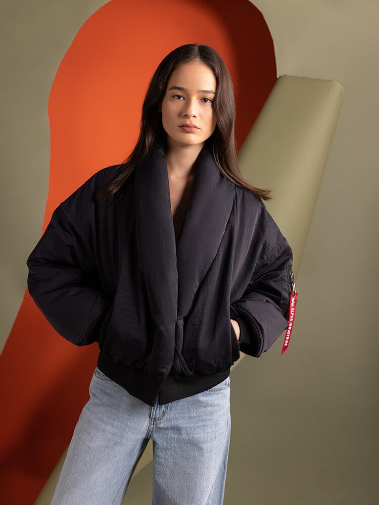 A person wearing the Women's Shawl Collar Bomber Jacket in black by Alpha Industries.