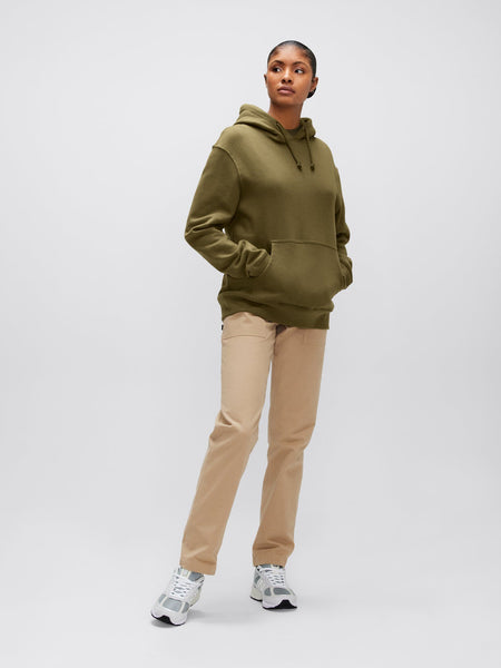 A person wearing the Alpha Hoodie in olive green from Alpha Industries, Inc., made from soft cotton fabric, pairs it stylishly with beige pants and white sneakers.