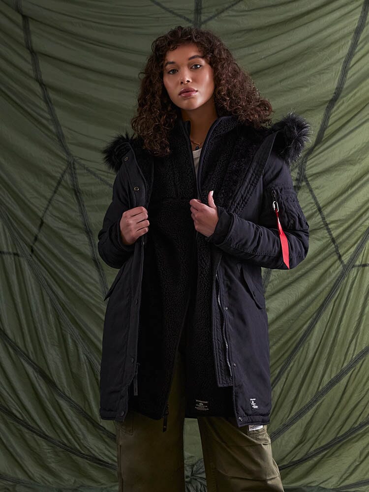 An individual wearing the Elyse Gen II Parka W in black from Alpha Industries, featuring a faux fur trim.