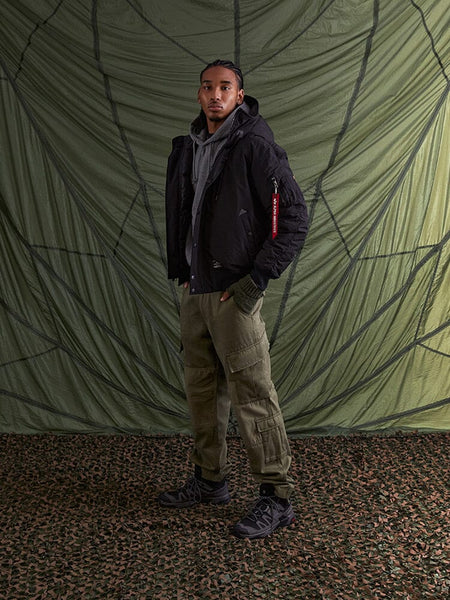 A person stands wearing the black Alpha Industries N-2B Altitude Parka.