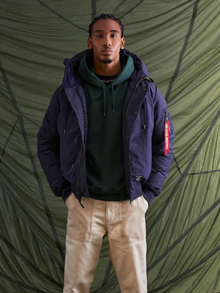 With confidence, the individual poses wearing the N-2B Altitude Parka in blue from Alpha Industries.