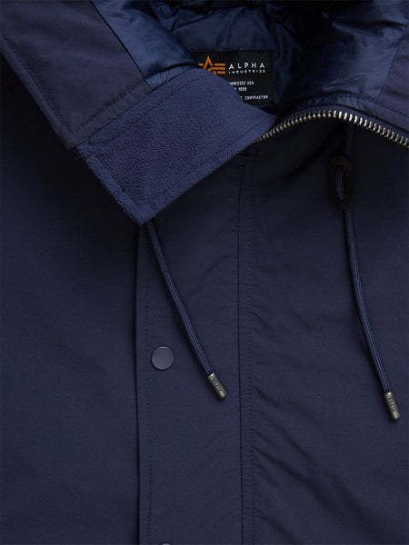 Close-up of a blue N-2B Altitude Parka highlighting its collar, zipper, drawstrings, and snap buttons. The inside label displays Alpha Industries with care instructions.