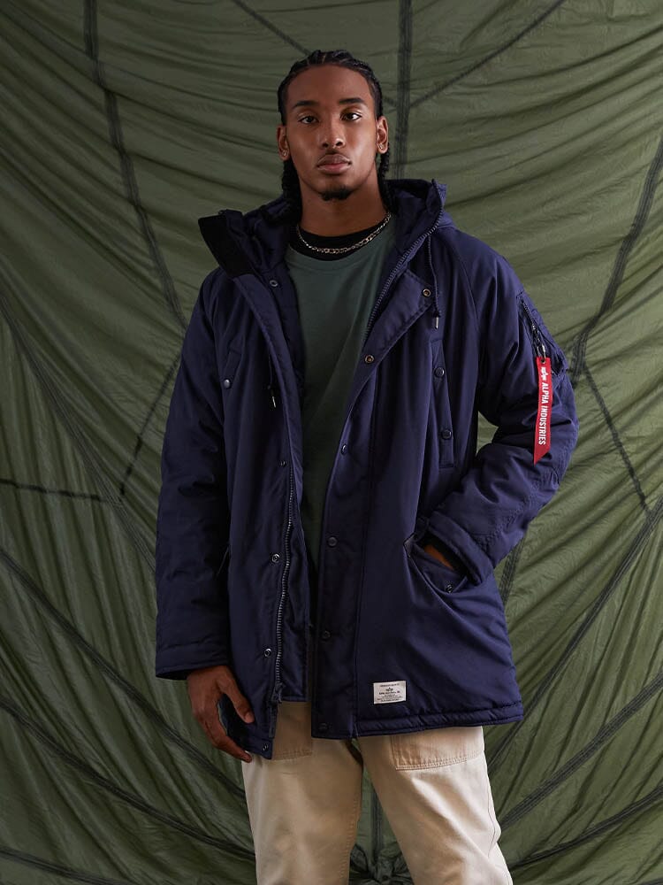 A person wearing the N-3B Altitude Mod Parka, a water-resistant blue hooded jacket by Alpha Industries.