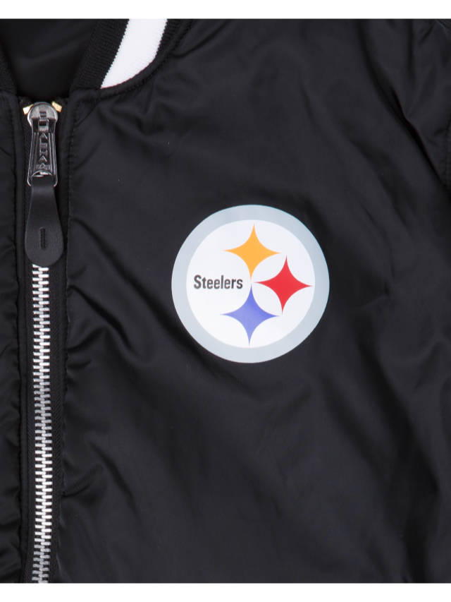 Close-up of the Pittsburgh Steelers x Alpha x New Era MA-1 Bomber Jacket in black, highlighting its zipper and circular Steelers logo with three colored stars (yellow, red, blue) on the chest. Produced by Alpha Industries / NE-NFL, this reversible jacket seamlessly blends style and versatility for any NFL fan seeking to showcase their team pride.