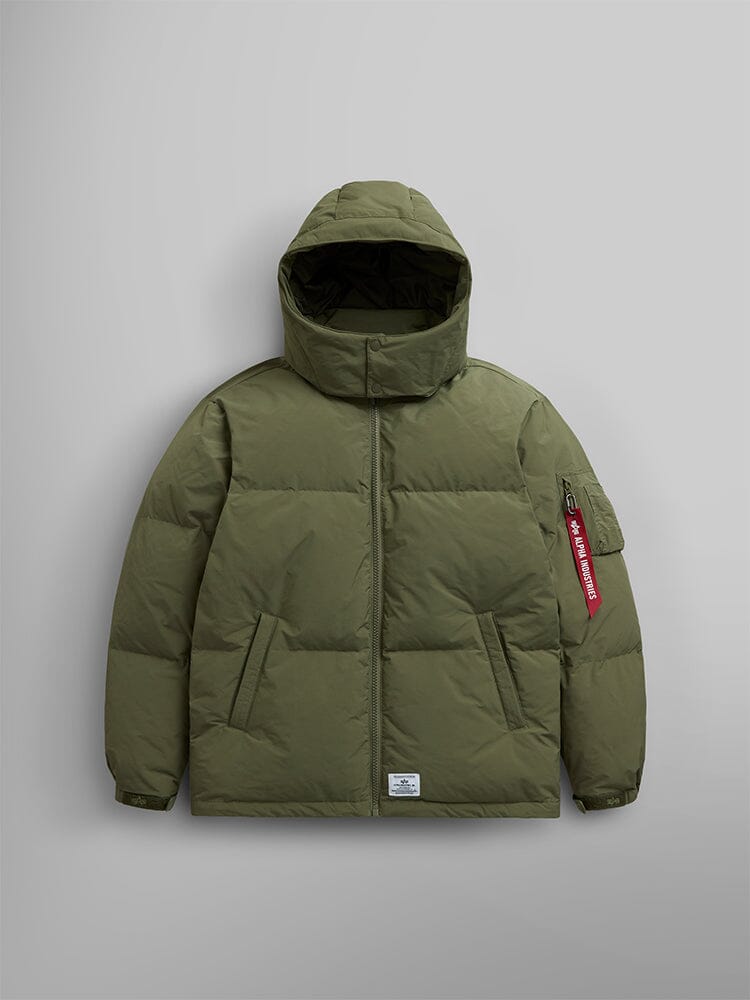 The Puffer Parka by Alpha Industries is showcased, featuring an OG-107 green color with a removable hood and adjustable drawcords, along with a distinctive red tag on the sleeve.